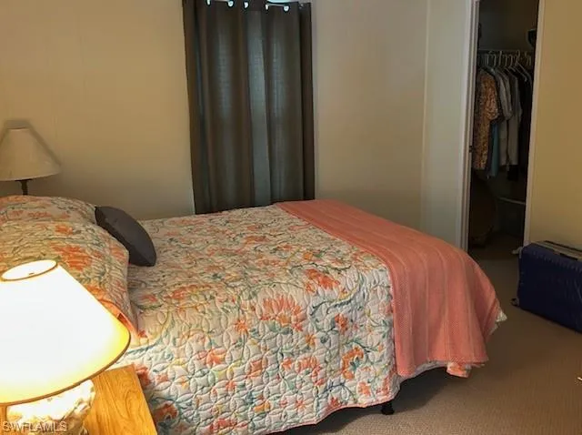 Carpeted bedroom featuring a walk in closet