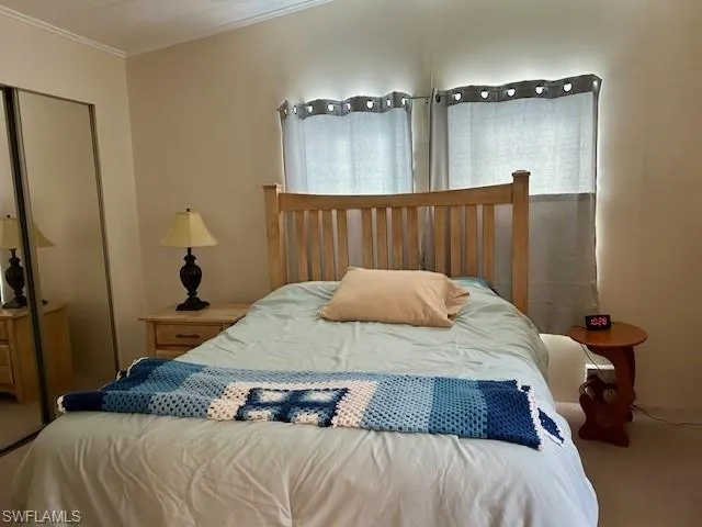 Carpeted bedroom with a closet and crown molding