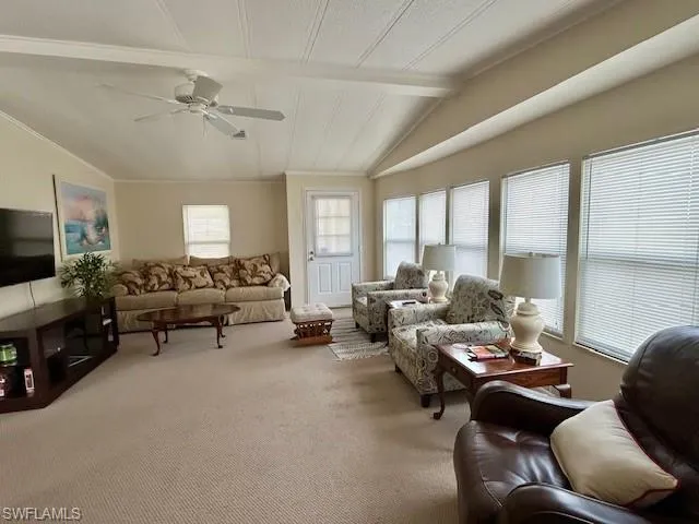 Carpeted living room with a ceiling fan