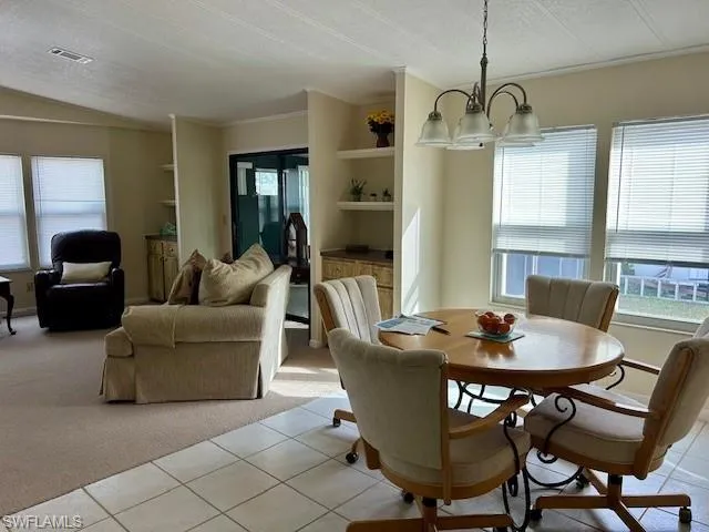 Dining area featuring built in shelves, light carpet, light tile patterned floors, a chandelier, and a textured ceiling