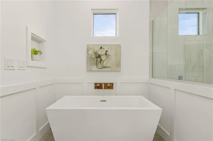 Bathroom with a tub to relax in, a healthy amount of sunlight, and hardwood / wood-style floors