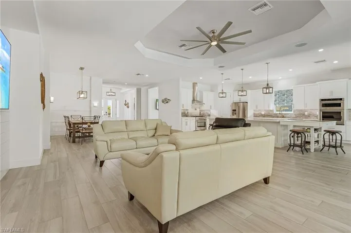 Living room featuring a raised ceiling, ceiling fan, sink, and light hardwood / wood-style floors