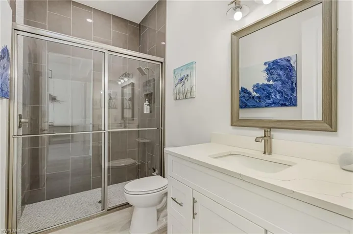 Bathroom with toilet, a shower with door, and vanity