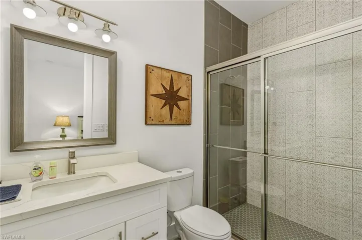 Bathroom featuring toilet, vanity, and an enclosed shower