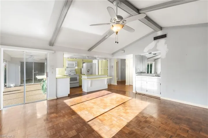 Kitchen featuring a ceiling fan, a kitchen island, white appliances, and plenty of natural light