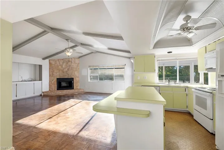 Kitchen featuring white appliances, light countertops, a center island, and a breakfast bar area