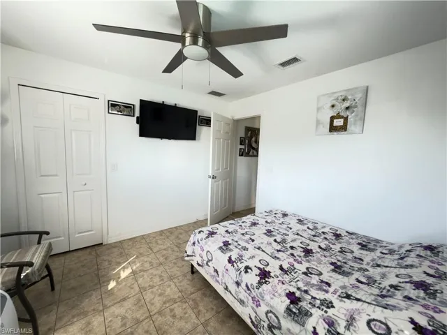 Bedroom with ceiling fan, a closet, and light tile patterned floors