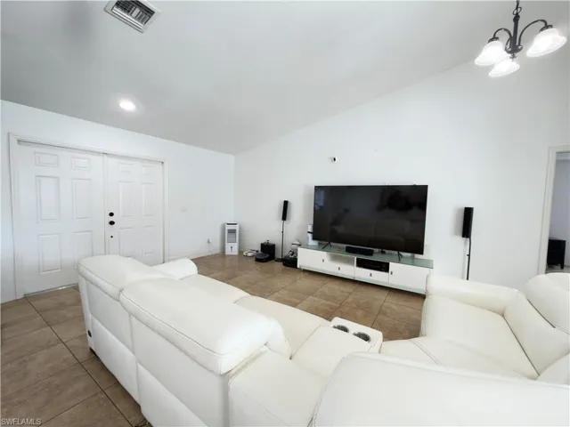 Living room featuring vaulted ceiling, light tile patterned floors, and a chandelier