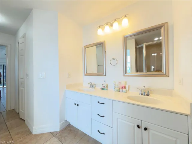 Bathroom featuring double vanity, light tile patterned floors, and a stall shower