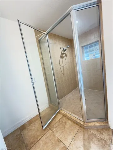Bathroom featuring a shower stall and light tile patterned flooring