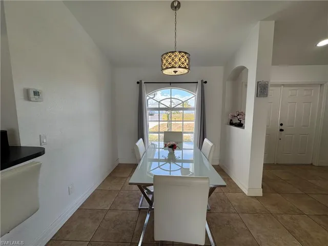 Dining area with light tile patterned floors and arched walkways