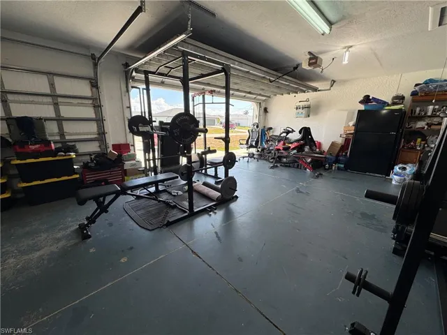 Garage with freestanding refrigerator, a textured wall, and a garage door opener