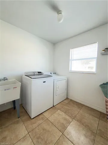 Laundry area with independent washer and dryer and light tile patterned flooring