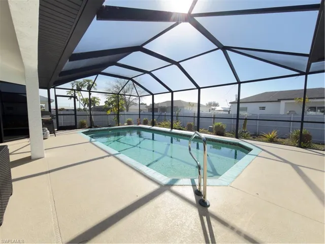 View of swimming pool featuring a fenced backyard, glass enclosure, patio surround, and a sunroom