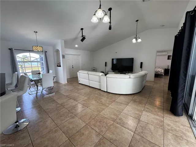 Living room featuring a chandelier, arched walkways, vaulted ceiling, and light tile patterned floors
