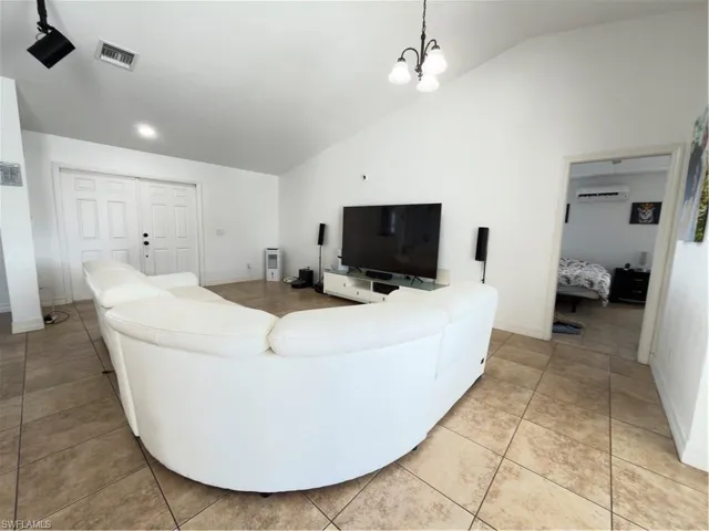 Living room featuring vaulted ceiling, light tile patterned floors, and hanging lights