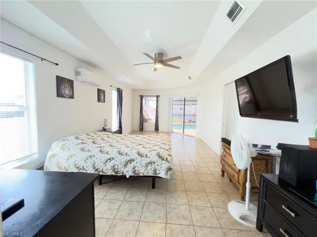 Bedroom with access to outside, a raised ceiling, light tile patterned flooring, and ceiling fan