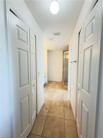 Hallway featuring light tile patterned floors and baseboards