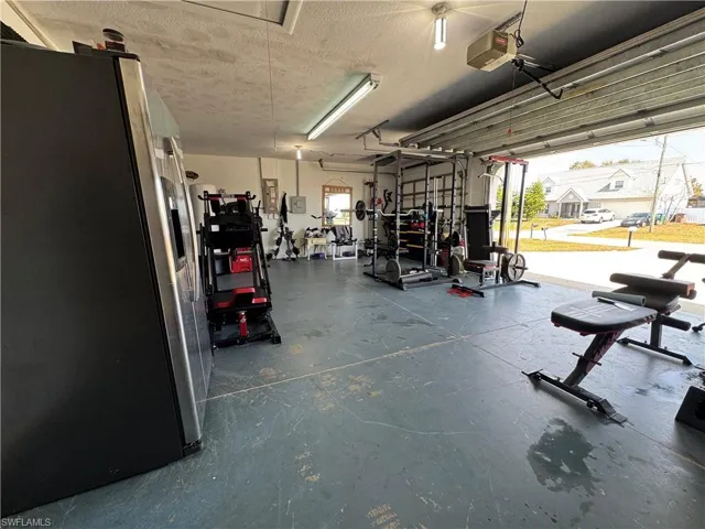 Garage featuring stainless steel fridge, a garage door opener, and a residential view