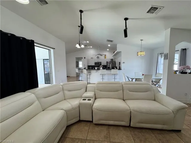 Living room featuring vaulted ceiling, a chandelier, and arched walkways