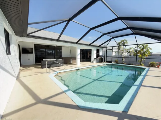 Outdoor pool featuring a sunroom, a patio area, and a lanai