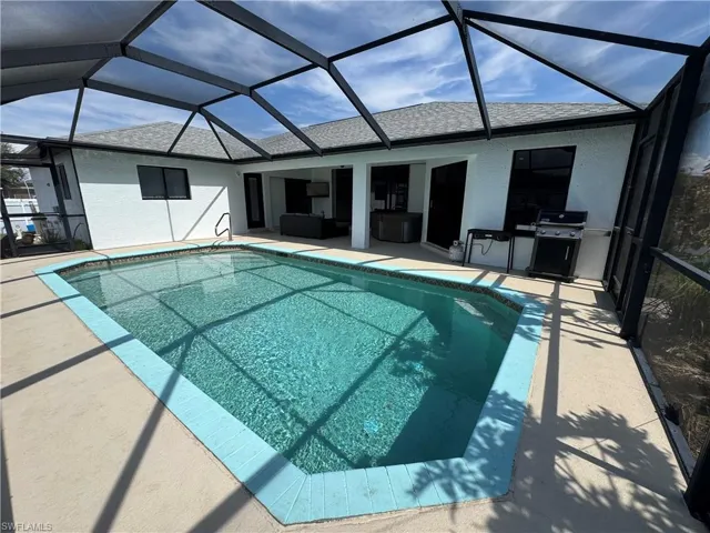 Swimming pool featuring a sunroom, glass enclosure, grilling area, and a patio