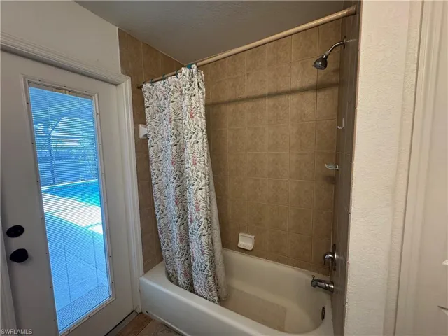 Bathroom featuring shower / bathtub combination with curtain and a textured ceiling