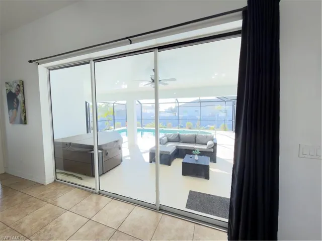 Doorway to outside with healthy amount of natural light, a ceiling fan, and tile patterned floors