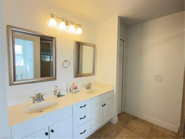 Bathroom with double vanity and light tile patterned floors