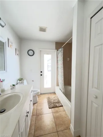 Bathroom with shower / tub combo, vanity, and light tile patterned floors