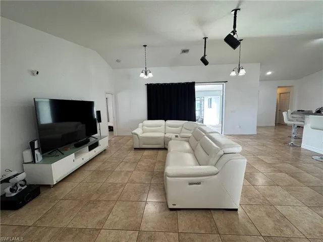 Living room featuring suspended lighting and vaulted ceiling