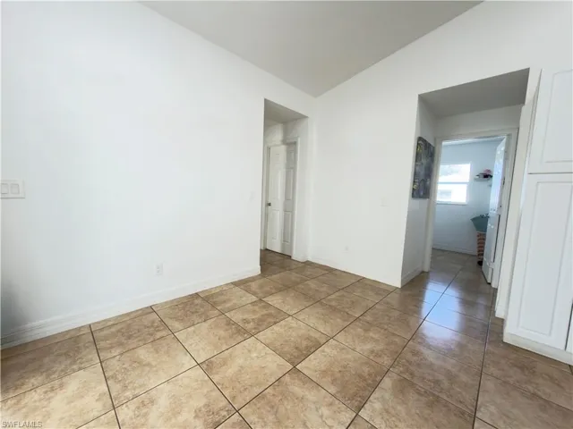 Empty room featuring lofted ceiling and light tile patterned flooring