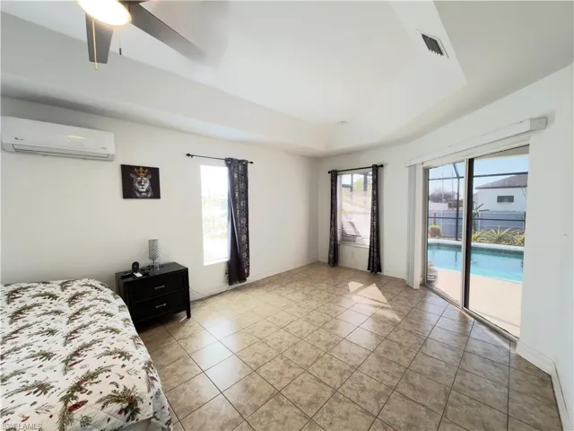Bedroom featuring access to outside, a ceiling fan, light tile patterned flooring, and a raised ceiling