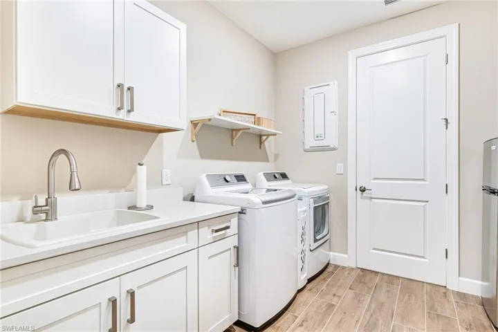 Laundry area with separate washer & dryer, laundry sink, and cabinet storage
