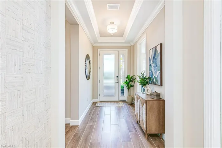 Foyer with wood plank tile floors, a tray ceiling and crown molding
