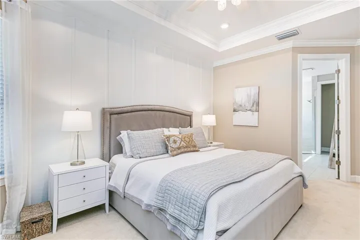 Bedroom featuring light colored designer carpet, a decorative accent wall, a raised ceiling