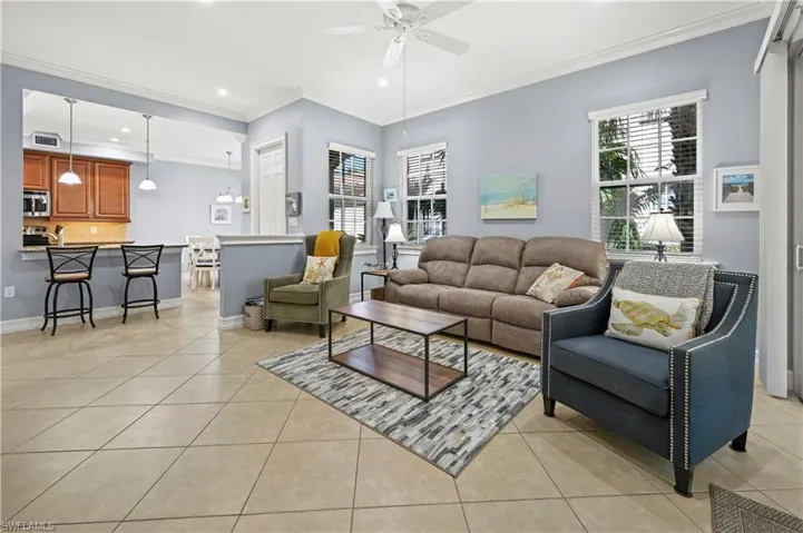Living area featuring light tile patterned floors, a healthy amount of sunlight, and a ceiling fan