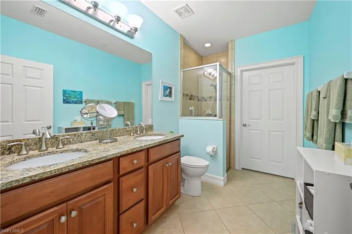 Full bath with tile patterned flooring, a walk in shower, dual sinks, and a walk in closet
