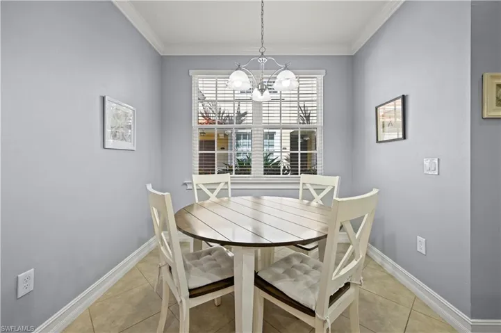 Dining area with baseboards, an inviting chandelier, light tile patterned flooring, and ornamental molding