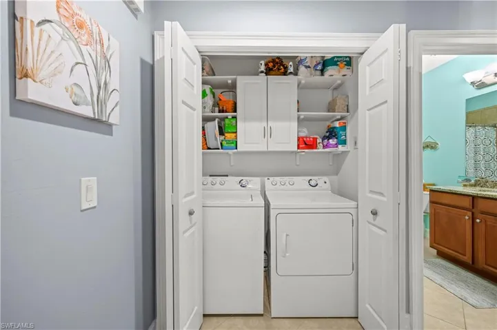 Laundry room with cabinet space, light tile patterned flooring, and washing machine and clothes dryer