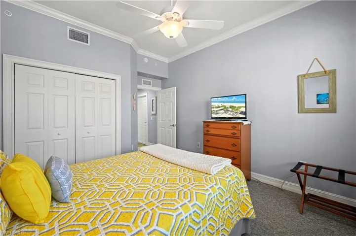Bedroom with a large closet, carpet flooring, and crown molding and ceiling fan