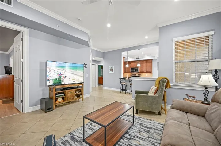 Living area featuring light tile patterned floors, a ceiling fan, and crown molding