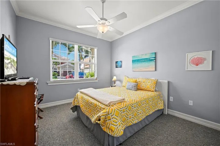 Carpeted bedroom featuring baseboards, a ceiling fan, and crown molding
