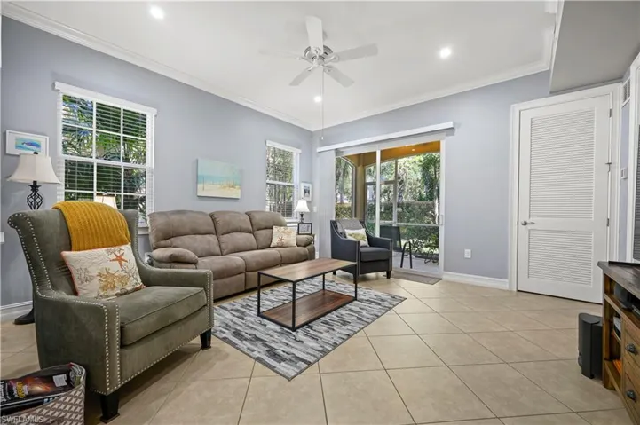 Living area with crown molding, light tile patterned flooring, and ceiling fan