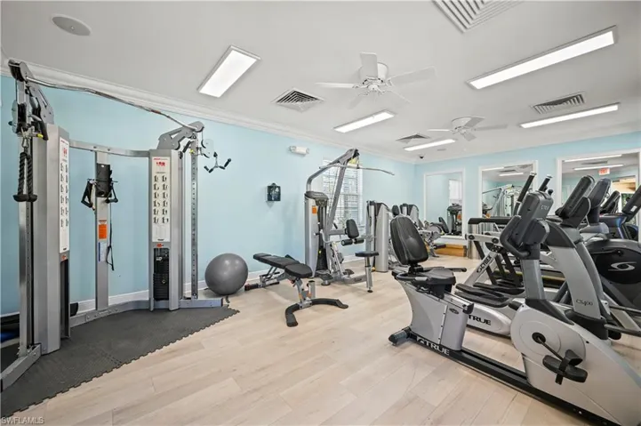 Workout area featuring visible vents, crown molding, ceiling fan, and wood finished floors