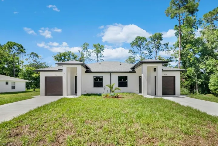 Contemporary duplex exterior featuring a white stucco finish, dark garage doors, and individual covered entryways