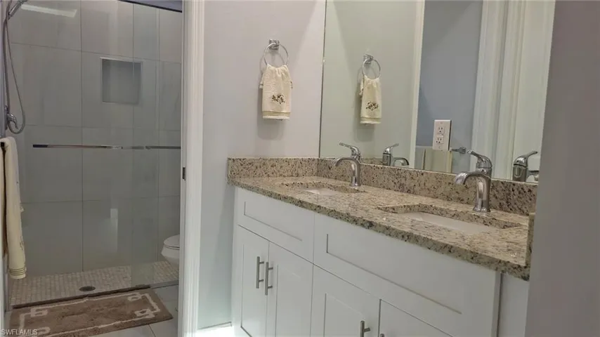 Full bathroom featuring double vanity and a stall shower