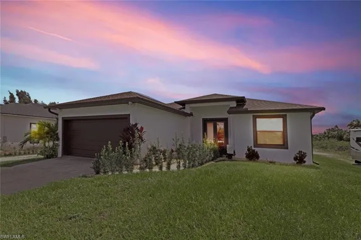 View of front of property featuring an attached garage, a front yard, stucco siding, and driveway