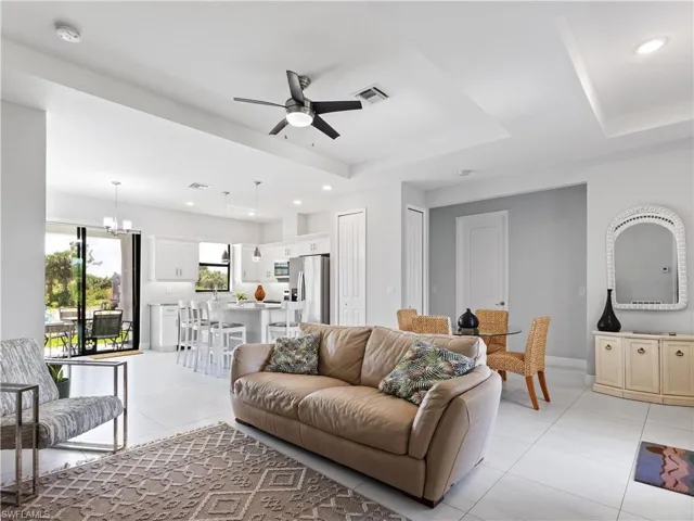 Living room featuring ceiling fan, suspended lighting, a raised ceiling, and light tile patterned floors