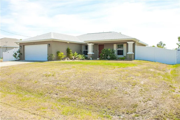 Ranch-style house with stucco siding, an attached garage, concrete driveway, and fence